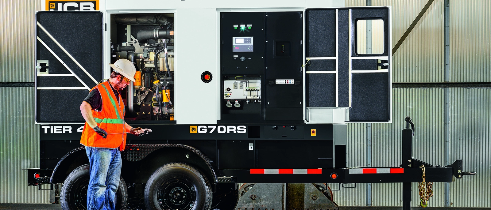Engineer in a hi-vis vest checking a trailer-mounted generator control panel